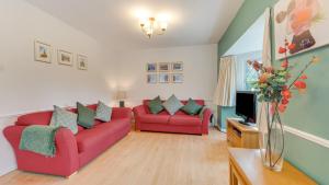a living room with two red couches and a tv at Stanton Lodge Cottage in Curbar