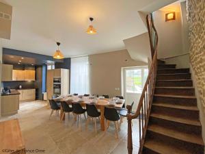 a dining room with a table and chairs and a staircase at Gîte de la Poste in Saint-Fraimbault-sur-Pisse