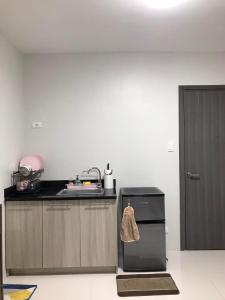 a kitchen with a sink and a black refrigerator at Camella Homes Bacolod Condo - Ibiza Bldg Unit 5O for rent! with WIFI and Netflix! in Bacolod