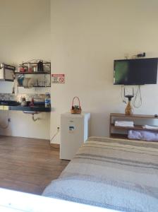 1 dormitorio con 1 cama y TV en la pared en CHALÉS MARICOTA, en Vargem Bonita