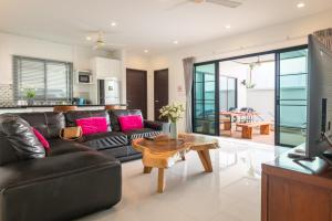 a living room with a black leather couch and a table at Thai-Themed 3br Boutique Villa by Intira Villas in Rawai Beach