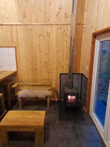a room with a wood stove and a bench at Entre Pampa y Bosque in Villarrica