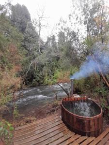 a hot tub on a wooden deck next to a river at Entre Pampa y Bosque in Villarrica