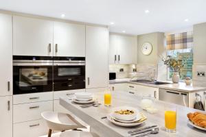 una cocina con armarios blancos y una mesa con comida en Fountains Executive Apartment - Harrogate Stays, en Harrogate