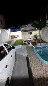 um carro branco estacionado ao lado de uma piscina à noite em CASA DE TEMPORADA RECANTO FELIz 2 em Aracaju