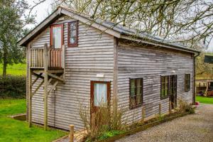 een klein huis met een veranda en een balkon bij 3-Bed Lodge with direct access to the Tarka trail in Great Torrington