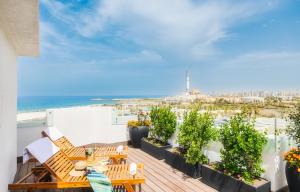 una mujer sentada en un balcón con vistas al océano en PLAY Seaport Suite Hotel TLV, en Tel Aviv