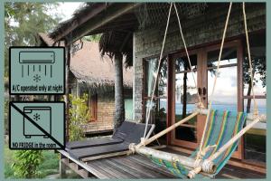 a hammock in front of a house with a sign at Coco Cottage - SHA Plus in Ko Ngai