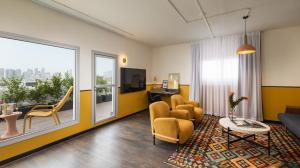 テルアビブにあるPLAY Seaport Suite Hotel TLVのリビングルーム(ソファ、椅子、テーブル付)