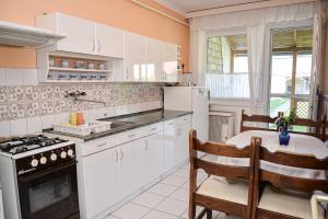 ハイドゥソボスローにあるLilla Vendégházのキッチン(白いキャビネット、テーブル、コンロ付)