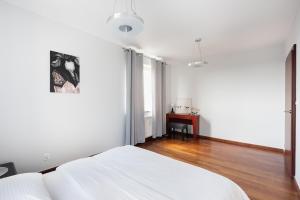 a white bedroom with a bed and a table at Mokotów Open Business Apartment in Warsaw