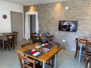 uma sala de jantar com mesas de madeira e uma televisão numa parede de tijolos em Sa Domo De Rosa em Budoni