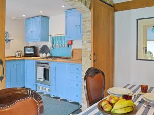 eine Küche mit blauen Schränken und einem Tisch mit einer Schale Obst in der Unterkunft The Barn At Butts Farm in Wicken