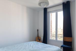 sypialnia z łóżkiem i oknem z gitarą w obiekcie Charming 35m near Paris w mieście Saint-Ouen