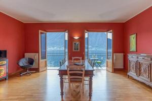 comedor con paredes rojas, mesa y sillas en Paolo's Home - overlooking the Lake en Colonno