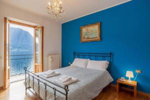 Dormitorio azul con cama y ventana grande en Paolo's Home - overlooking the Lake en Colonno