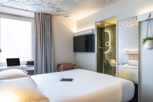 um quarto de hotel com uma cama branca e uma janela em ibis Paris Nation Davout em Paris