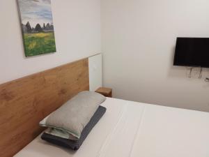 Schlafzimmer mit einem weißen Bett und einem Flachbild-TV in der Unterkunft Vila Cissa in Novalja