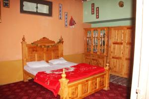 a bedroom with a large wooden bed with red sheets at Rakaposhi Amin Hotel & Restaurant Pissan Hunza Nagar Gilgit Baltistan in Gilgit +249 photos