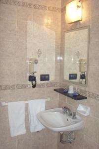 a bathroom with a sink and a mirror and towels at Hotel Embajador in Rosario