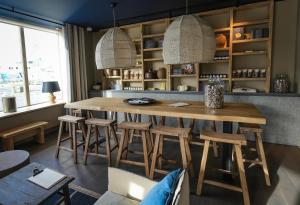 a dining room with a wooden table and stools at Otonali Hôtel by Breizh Café in Saint Malo