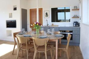 a kitchen with a table and chairs with wine glasses at Eco-Lodge with sea view Charleton Estate in Colinsburgh