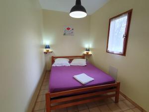 1 dormitorio con cama morada y ventana en Les Chalets du Gélat, nature et calme, en Noaillan
