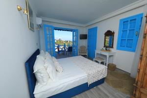 1 dormitorio con puertas azules, 1 cama y balcón en Bellapais Abbey Boutique Hotel en Kyrenia