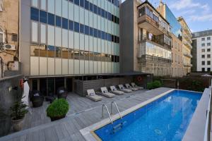 una piscina de hotel con tumbonas y un edificio en Catalonia Square 4* Sup, en Barcelona