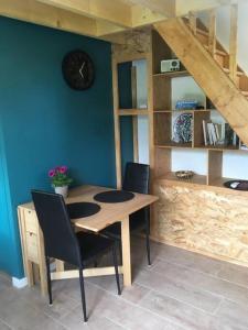 een eettafel met stoelen en een klok aan een muur bij Appartement avec jardin privé Gréoux les Bains au bord du Verdon in Gréoux-les-Bains