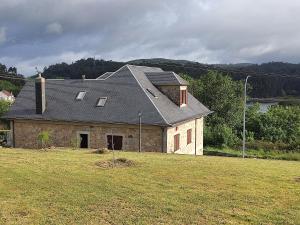 ein Steinhaus mit einem Dach auf einem Feld in der Unterkunft Casa da Escuela in Caldas de Reis