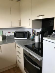 a kitchen with white cabinets and a black microwave at Birslack Grange in Kendal