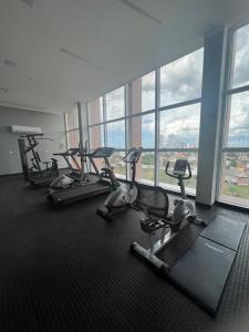 um ginásio com várias máquinas de piso numa sala com janelas em Apartamento de Alto Padrão Recém Inaugurado em Campina Grande