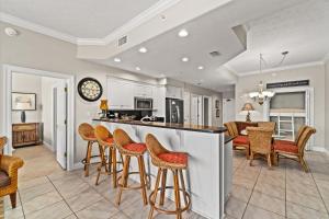 a kitchen with bar stools and a dining room at Treasure Island 0507 in Panama City Beach