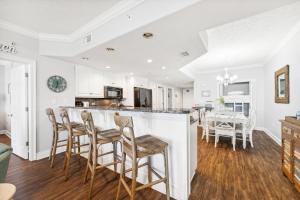 a kitchen and dining room with white walls and wood floors at Treasure Island 2109 in Panama City Beach