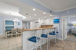 a kitchen and dining room with a counter and stools at Treasure Island 0110 in Panama City Beach