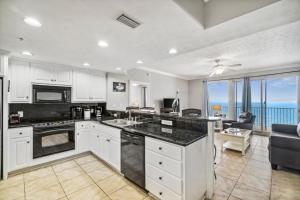 a kitchen with white cabinets and a view of the ocean at Treasure Island 1808 in Panama City Beach