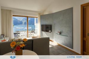 ein Wohnzimmer mit einem Tisch und einem großen Fenster in der Unterkunft Parco San Marco Lifestyle Beach Resort in Porlezza