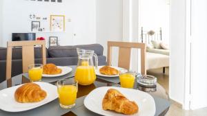 a table with plates of croissants and glasses of orange juice at Home Amatista Málaga in Málaga +31 photos