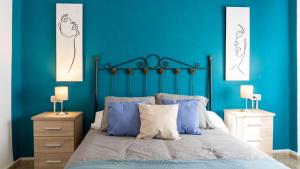 a bedroom with blue walls and a bed with blue pillows at Home Amatista Málaga in Málaga