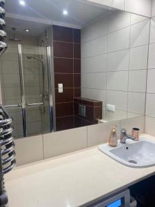 a bathroom with a sink and a shower with a mirror at Przestronny apartament in Giżycko