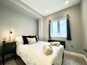 een slaapkamer met een bed met witte lakens en een raam bij Stylish 2 Bed Apt - Watford Gen Hospital - Watford FC - Professionals & Contractors Welcome in Watford