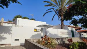 a white house with a palm tree and an umbrella at Marga STUDIO H10 in Arona