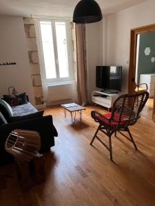 a living room with a couch and a tv at Nid douillet T2 wifi centre historique 3 étoiles in La Rochelle