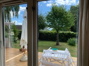 uma porta de vidro deslizante com uma mesa e uma cadeira num deque em Traditional Danish Summer House em Hornslet