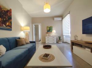 een woonkamer met een blauwe bank en een tafel bij Ciauru i mari - Elegante appartamento Ortigia in Siracusa