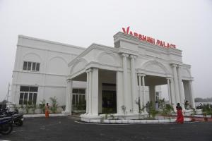 a white building with a sign on top of it at Varshini Palace 