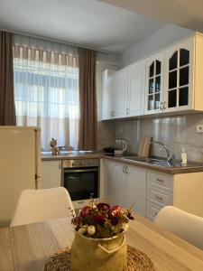 a kitchen with white cabinets and a table with a bowl on it at SaEl Apartments in Shkodër
