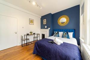 1 dormitorio con 1 cama con pared azul en Super Central Studio Apartment I Next to Brighton Beach & Shopping Centre I KING SIZE BED I SLEEP 3, en Brighton & Hove