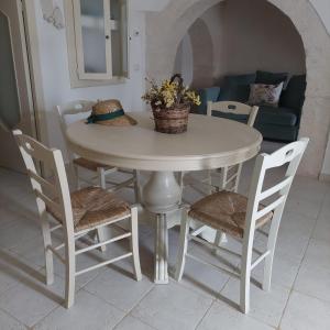 a white table with chairs and a table with flowers on it at I Trulli di Nonna Maria in Alberobello +16 photos
